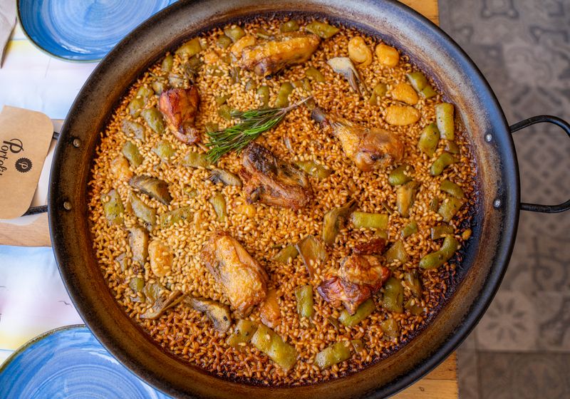 Paella valenciana de pollo recién hecha en su paellera
